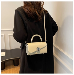 Detail of minimalist cream box bag with silver spherical clasp and leather handle