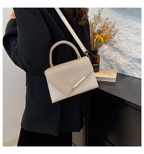 Close-up of a luxury cream handbag with sparkling rhinestone details and gold hardware