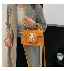 Detail view of stylish orange leather crossbody bag with oversized gold metal buckle