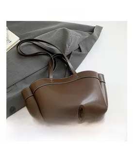 Dettaglio della borsa tote in pelle marrone scuro con cuciture bianche e doppi manici
