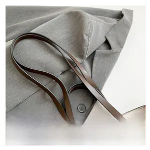 Dettaglio del manico in pelle marrone con cuciture bianche a contrasto della borsa