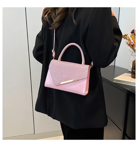 Detail of pink crossbody bag with sparkling flap and gold hardware worn by a model