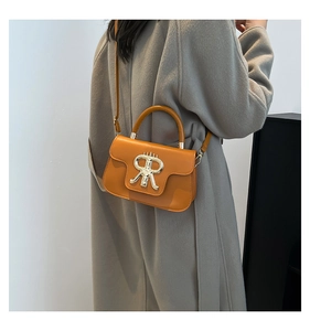 Detail of orange leather square handbag with golden R-buckle worn on grey wool coat