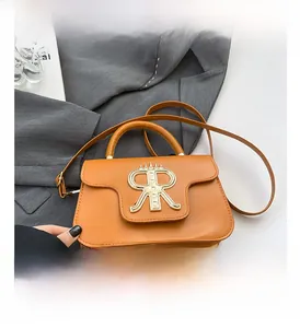 Close-up of ginger yellow crossbody bag with gold RR logo on gray blazer backdrop