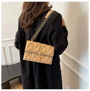 Detail of light brown quilted crossbody bag with gold SS logo and chain strap on model