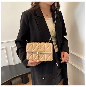 Détail d'un sac bandoulière matelassé beige avec chaîne dorée et logo métallique