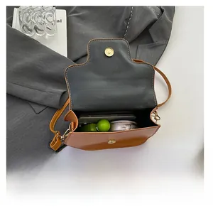 Interior view showing capacity for smartphone and cosmetics in brown leather crossbody bag