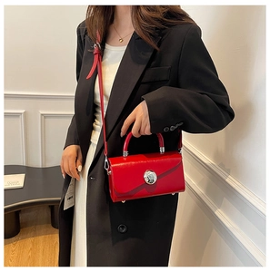 Detailed side view of bright red glossy handbag featuring silver metallic buckle closure