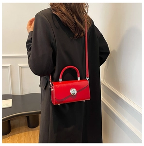 Side view of a bright red glossy leather box handbag styled with a black blazer
