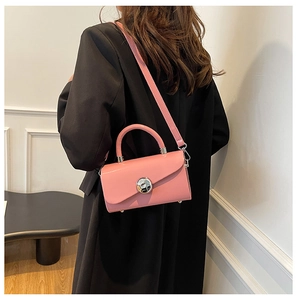 Pink patent leather handbag with silver lock shown on a black suit blazer model