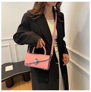 Pink mini box handbag with glossy leather finish and silver spherical buckle worn by model