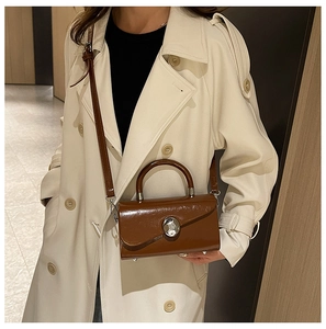 Close-up of brown glossy leather box bag with a unique silver spherical metal clasp