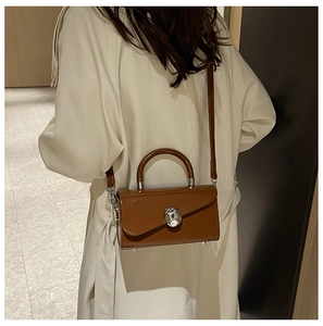 Retro dark brown leather box bag styled with an elegant cream trench coat on a model