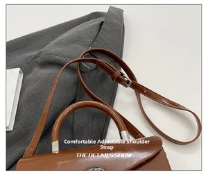 Detail of adjustable brown leather shoulder strap with silver buckle on minimalist box bag