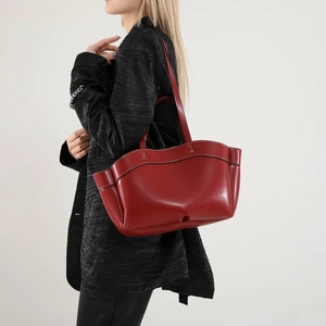 Borsa tote in pelle rosso scuro con bordo ondulato e cuciture a contrasto su modella
