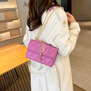 Sac bandoulière matelassé magenta tendance avec chaîne dorée et pompon sur modèle