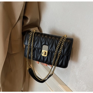 Detail of black quilted leather shoulder bag with gold twist lock and chain strap