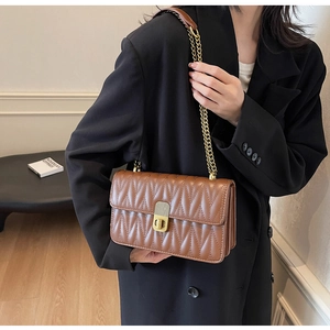 Brown quilted chain bag shown on model featuring gold twist lock and elegant texture