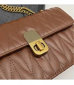 Detailed macro view of brown quilted leather texture and golden metal rotary lock on handbag