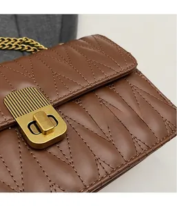 Detail of brown quilted leather texture with vintage gold lock and chain strap
