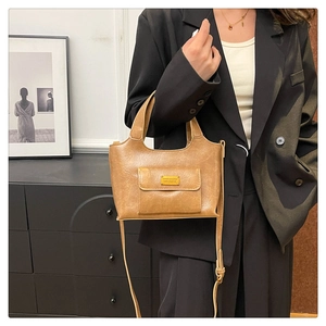 Gros plan du sac à main caramel avec logo doré et détail de poche à rabat frontale