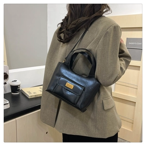 Détail d'un sac seau en cuir noir porté par un mannequin en blazer pour un look chic urbain