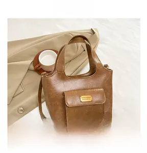Détail du sac cabas marron avec plaque logo dorée et bandoulière réglable pour femme