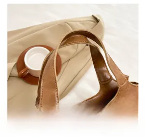 Gros plan sur la poignée d'un sac en cuir marron vintage avec coutures et boucle métal