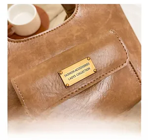 Détail d'un sac seau vintage en cuir marron avec logo métallique et coutures de précision