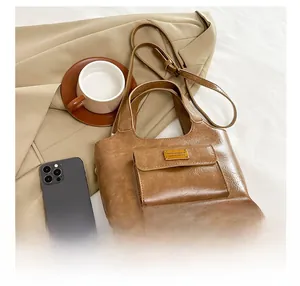 Détails de la texture du cuir PU marron vintage et logo doré sur le sac pour femme