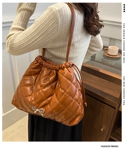 Detail of caramel quilted bucket bag with silver bow accent and drawstring closure