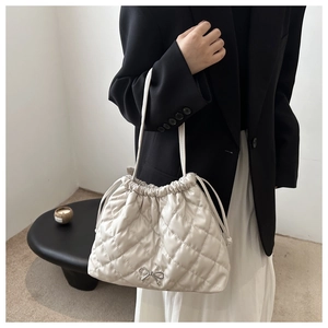 Close-up of quilted drawstring tote bag with silver bow detail on a stylish model