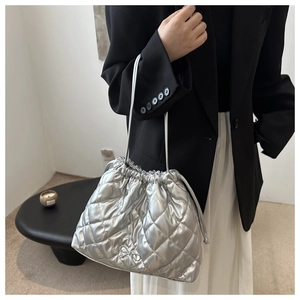 Detail of silver quilted bucket bag with a delicate metal bow clasp and drawstring closure