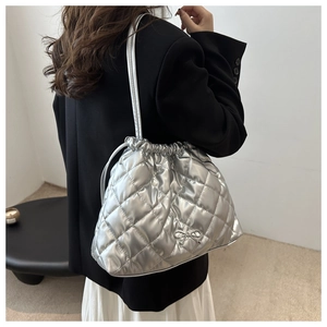 Close-up of silver quilted drawstring bucket bag featuring a metallic bow decoration