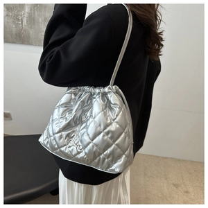 Detail of silver quilted handbag with metallic finish and delicate metal bow accessory