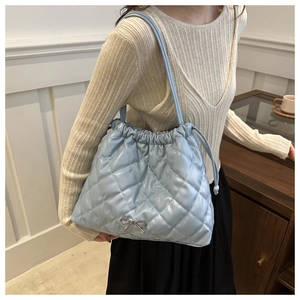 Detail of light blue quilted bucket bag with silver bow accent and drawstring closure
