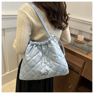 Detail of light blue quilted tote bag with silver bow accent and drawstring closure