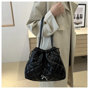 Close-up of black quilted bucket bag with silver bow detail and drawstring closure