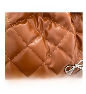 Close-up of caramel quilted leather texture with silver bow metal hardware detail