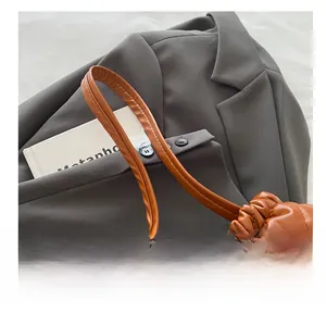 Detail of brown quilted leather bucket bag with drawstring closure on gray blazer
