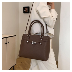 Modell zeigt dunkelbraune Handtasche aus Litschi-Leder mit Silberverschluss und Tragegurt