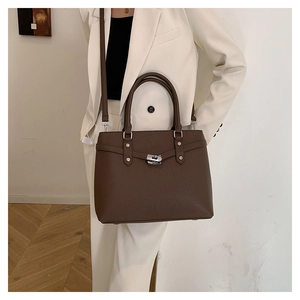 Details der Handtasche mit Litschistruktur, silbernem Drehverschluss und Schultergurt