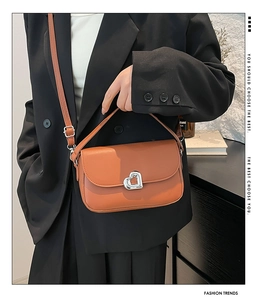 Close-up of caramel saddle bag featuring a silver heart buckle and adjustable strap