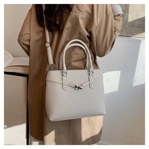 Detailaufnahme der cremefarbenen Ledertasche mit Silberverschluss und Textur am Modell