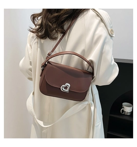 Close-up of the vintage brown saddle bag featuring a silver heart-shaped metal twist lock