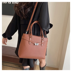 Detail einer braunen Tote-Bag mit Litschi-Muster und silbernem Metall-Drehverschluss