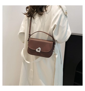 Side view of dark brown saddle bag with silver heart buckle on trench coat model