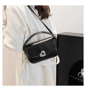 Detail of a chic black leather small square bag featuring a silver heart-shaped lock buckle