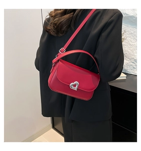 Detail of red leather crossbody bag with silver heart buckle on a black blazer outfit