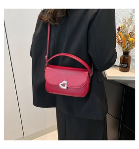 Detail of burgundy leather handbag featuring a silver heart-shaped rotating lock closure